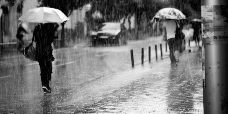 a-person-shields-themselves-with-an-umbrella-while-walking-in-the-heavy-rain-on-a-city-street-free-photo